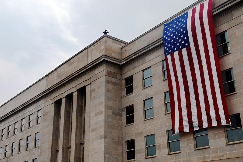 An American flag hangs over the point of impact of the Sept. 11, 2001, attack on the Pentagon for a wreath laying observance of the attacks, near Washington